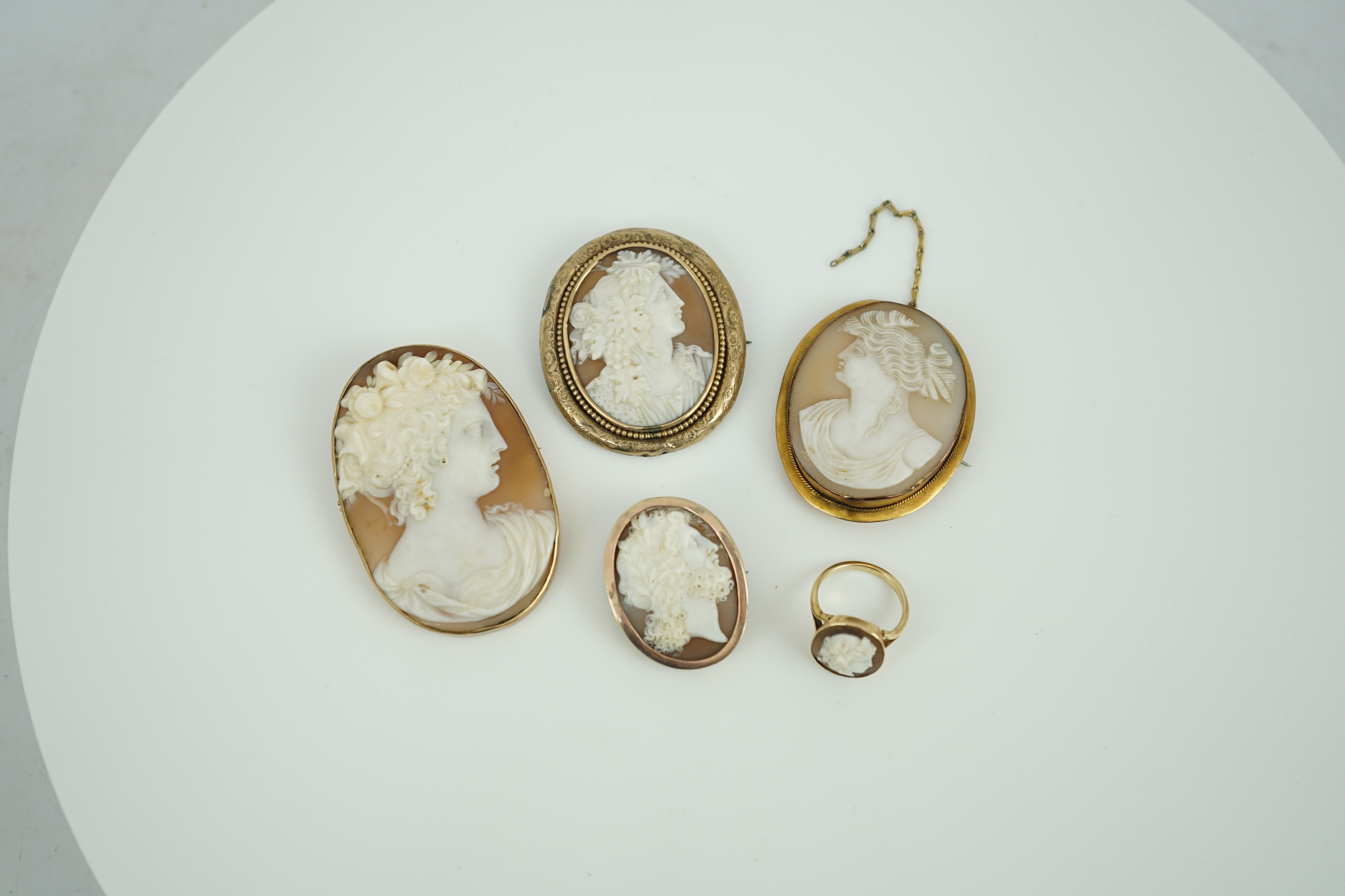 Four assorted early 20th century yellow metal mounted oval cameo shell brooches, largest 60mm, one stamped 9ct and a yellow metal mounted oval cameo shell ring.